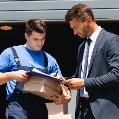 loader-holding-carton-box-while-businessman-in-sui-2023-11-27-05-02-36-utc-1024x684